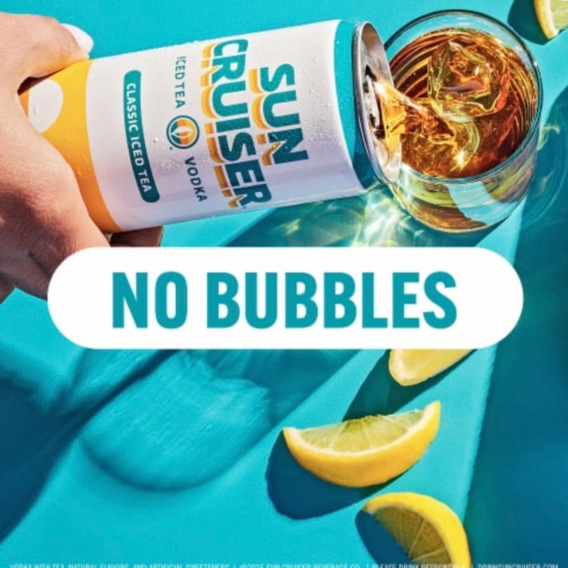 A hand pours a Sun Cruiser Classic Iced Tea Vodka from a can into a glass with ice and lemon slices.