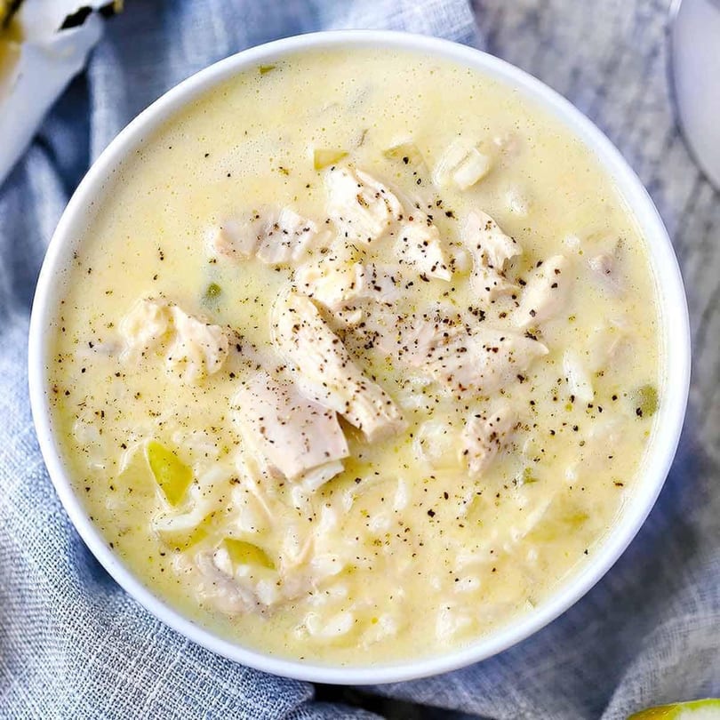 Creamy chicken and rice soup, generously seasoned with black pepper, in a white bowl.