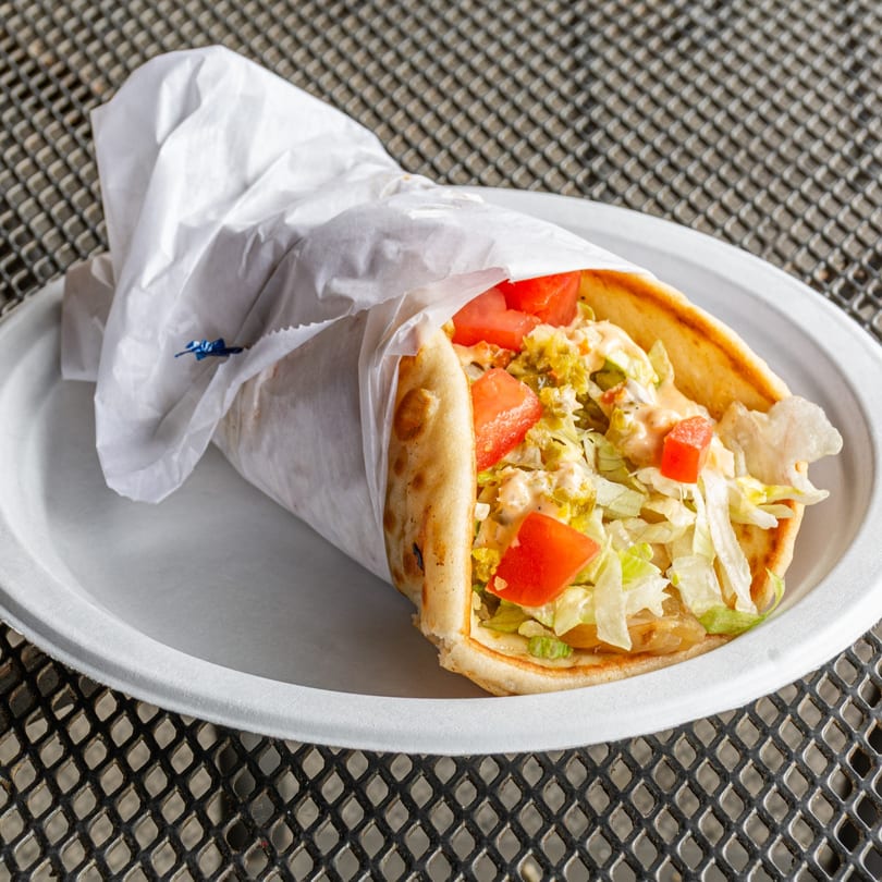 A Jefferson Street Pub gyro, wrapped in paper, filled with meat, lettuce, tomatoes, and sauce.